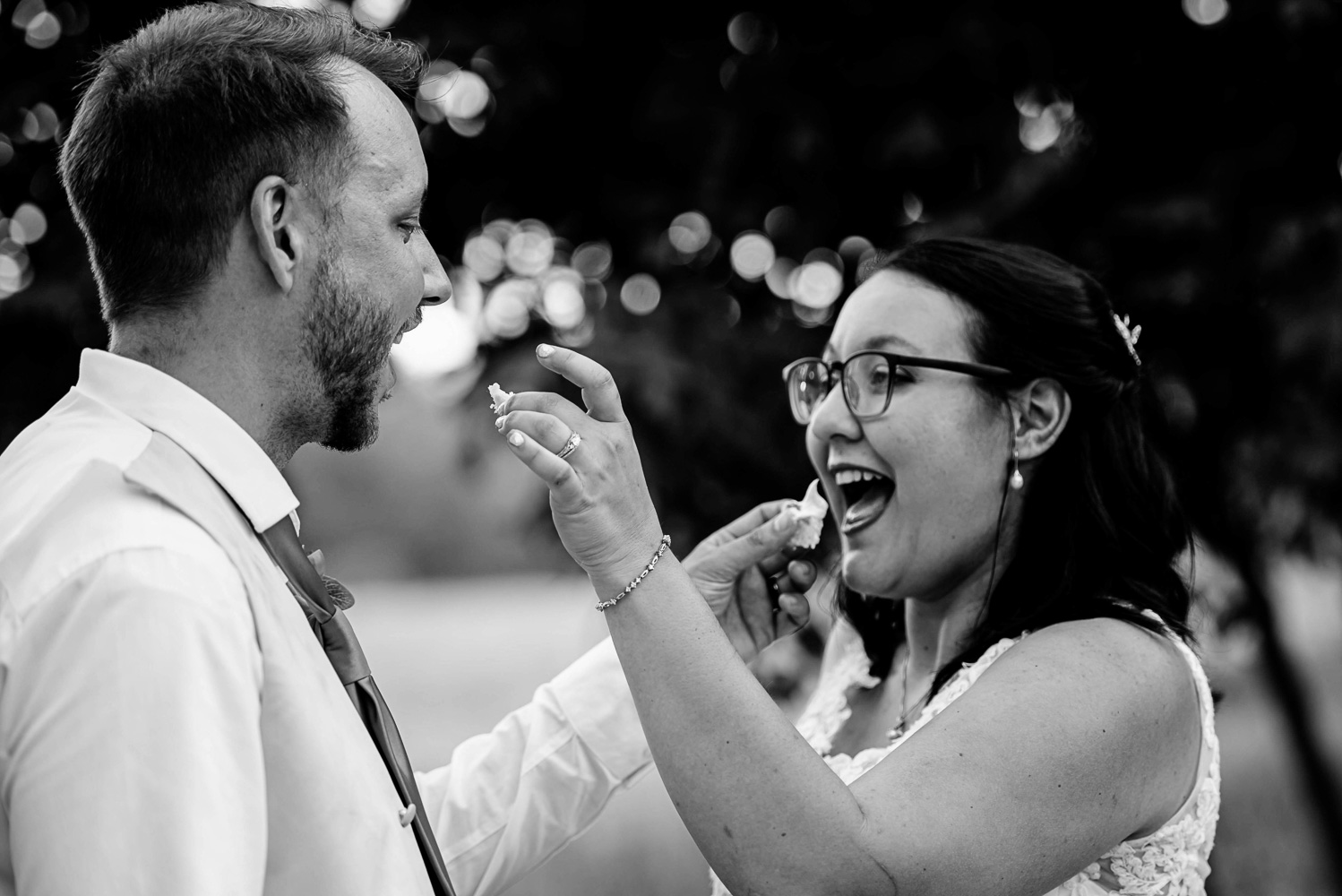 bride and groom feeding each other cake on their wedding day at their summer wedding at home