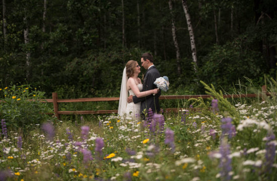 bride and groom hugging in a field of wildflowers at Pine Peaks Lodge in Minnesota