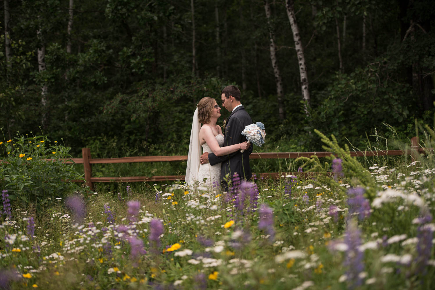 bride and groom hugging in a field of wildflowers at Pine Peaks Lodge in Minnesota