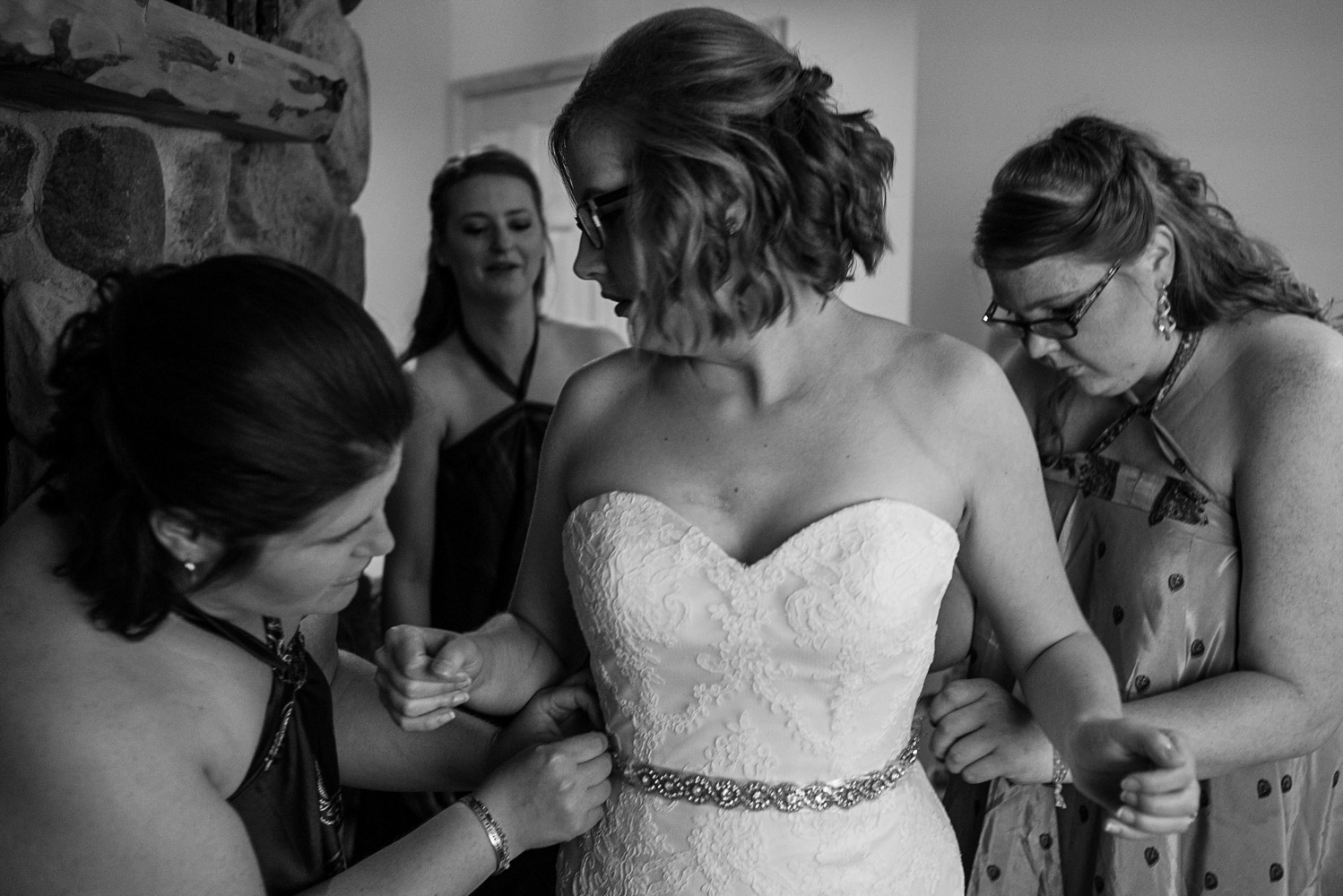 bride getting her dress buttoned by her bridesmaids