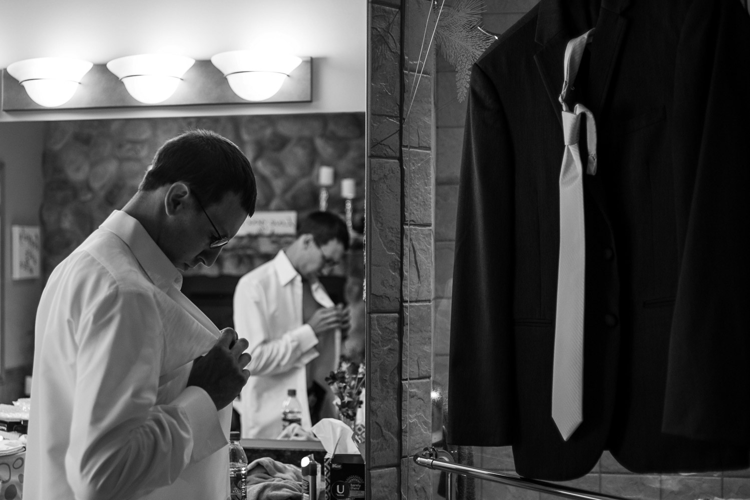 groom buttoning his shirt while getting ready on his wedding day at Pine Peaks Lodge in Northern Minnesota