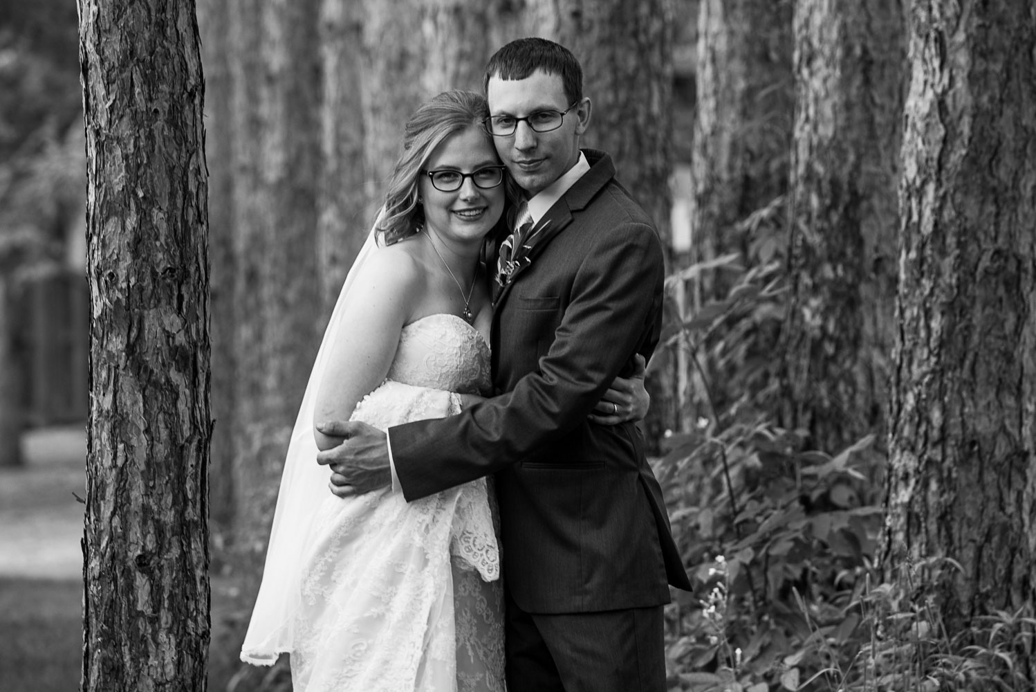 bride and groom hugging next to pine trees in Northern Minnesota