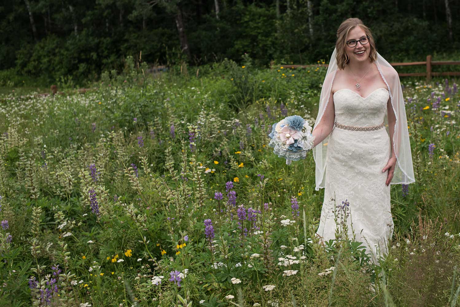 bride holding her bouquet while standing in a field of wildflowers in up north