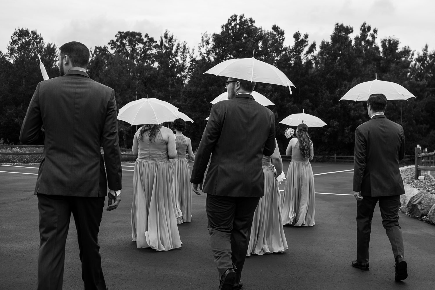 wedding party walking with umbrellas at Pine Peaks Lodge in Minnesota