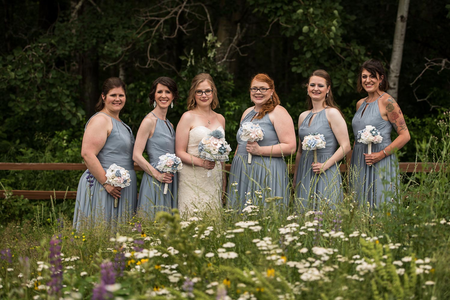 bride with her bridesmaids with light blue bridesmaid dresses while standing in a field of wildflowers at Pine Peaks Lodge in Crosslake Minnesota