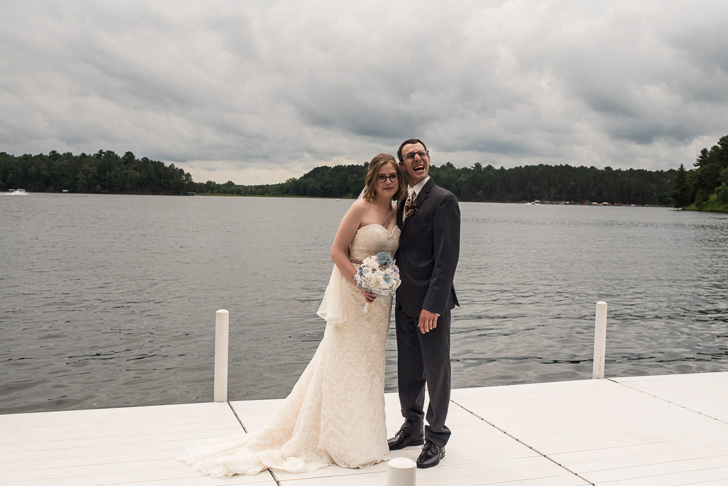 bride and groom standing on a dock next to a lake in Crosslake Minnesota