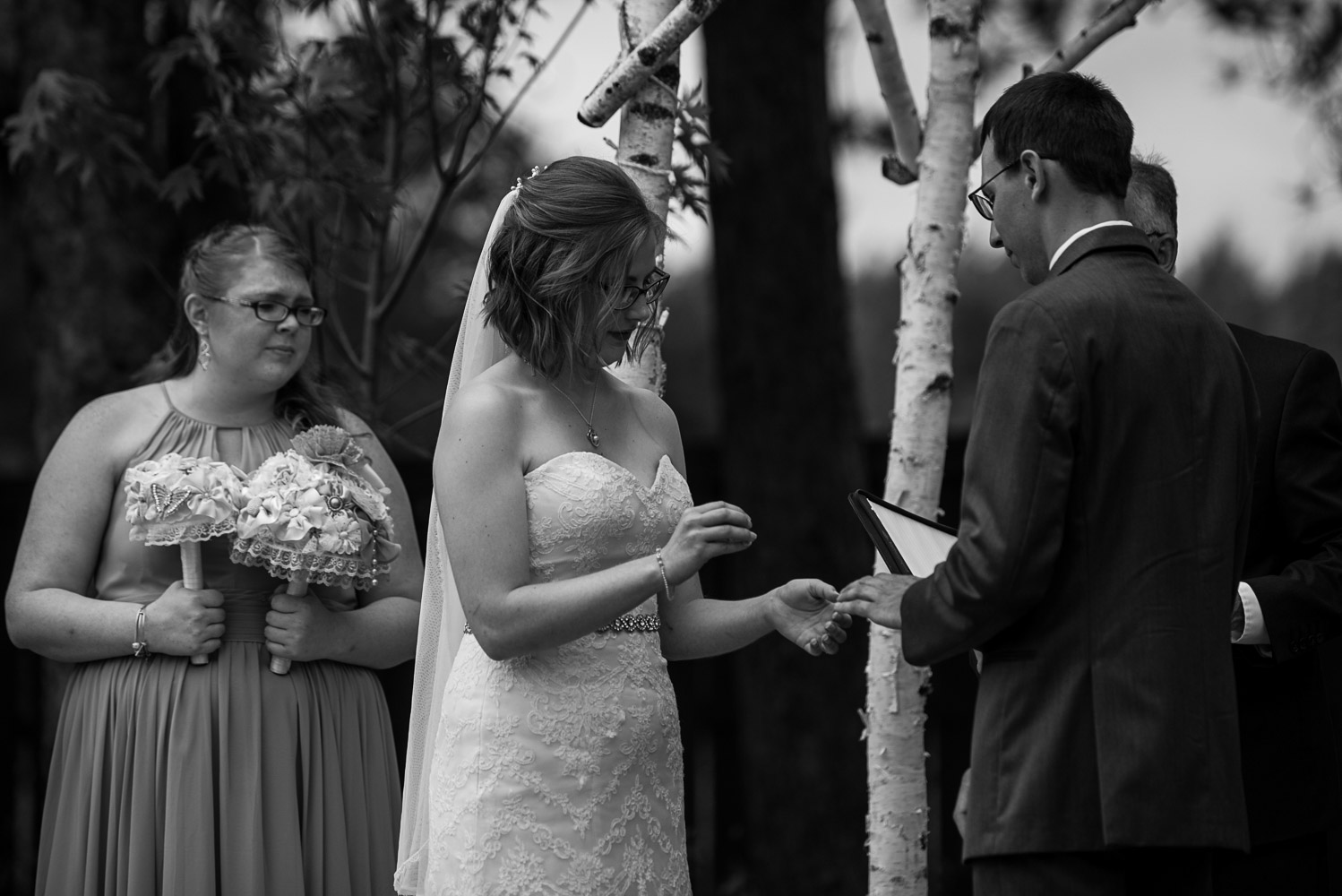 bride and groom exchanging rings during their wedding ceremony at Pine Peaks Wedding and Event CenterLodge in Crosslake Minnesota