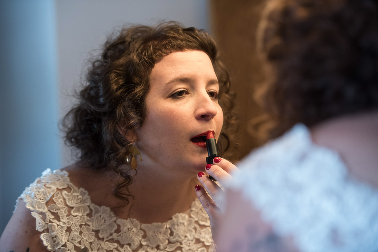 bride putting on her lipstick in front of a mirror 