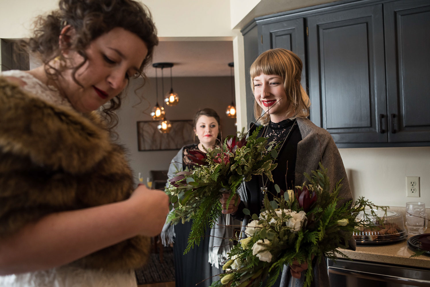 bride and bridesmaids putting on fur capes and holding their bouquets 