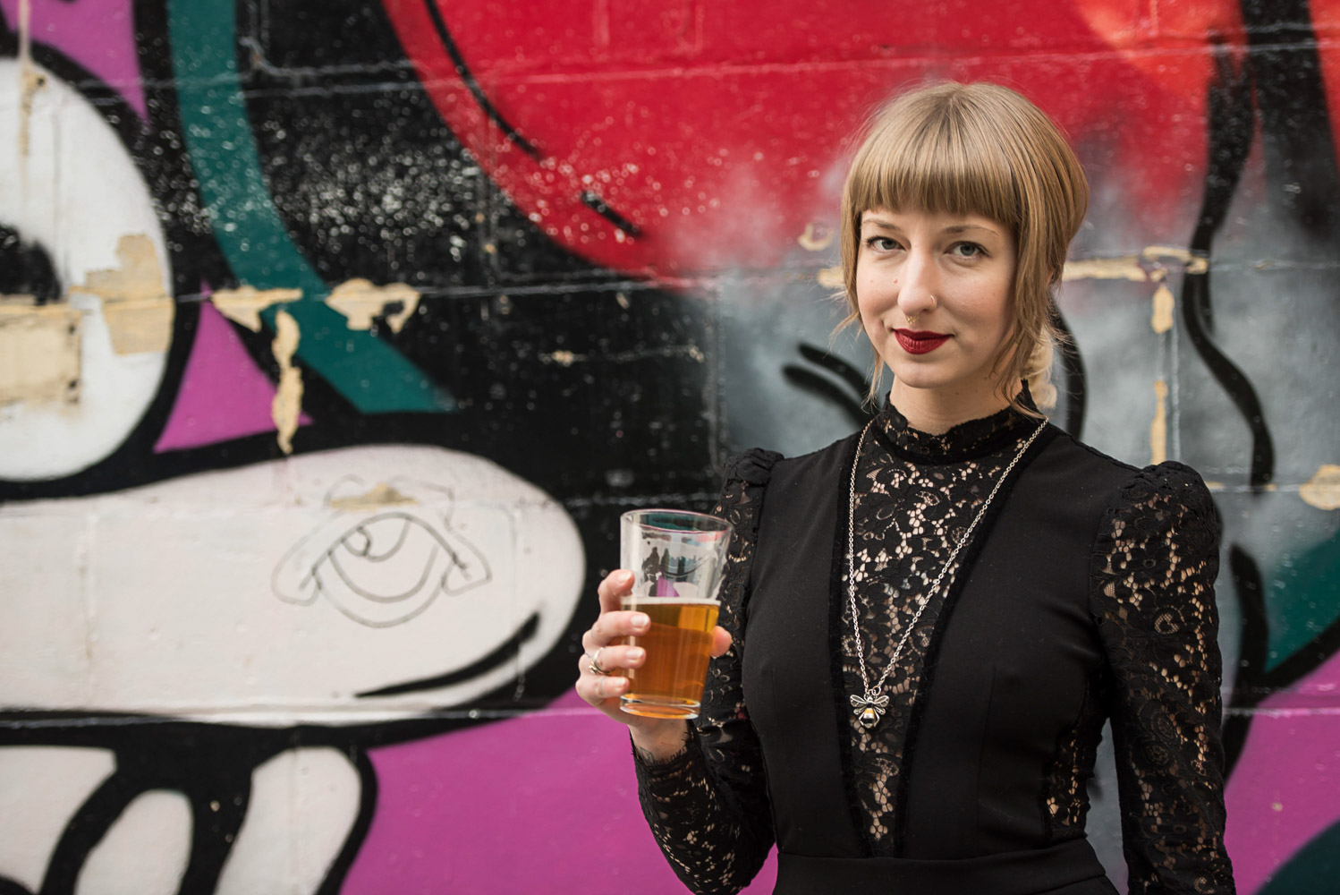 bridesmaid drinking a beer standing next to a graffiti wall behind Turtle's 1890 Social Centre 
