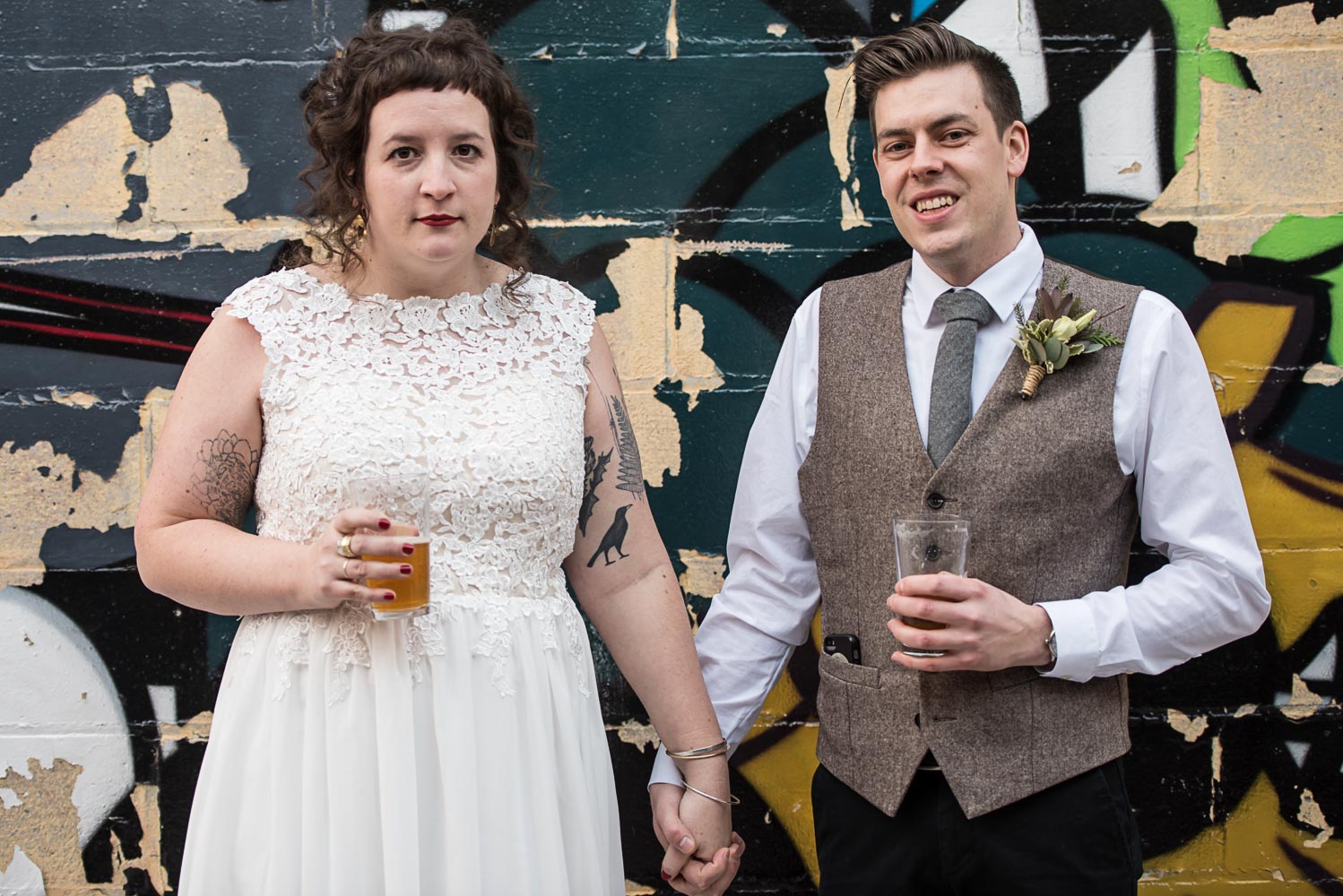 bride and groom having a beer next to a graffiti wall behind Turtle's 1890 Social Centre 