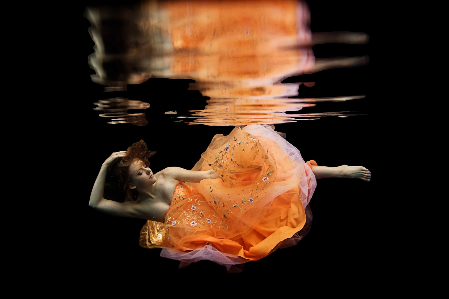 girl in an orange prom dress underwater 