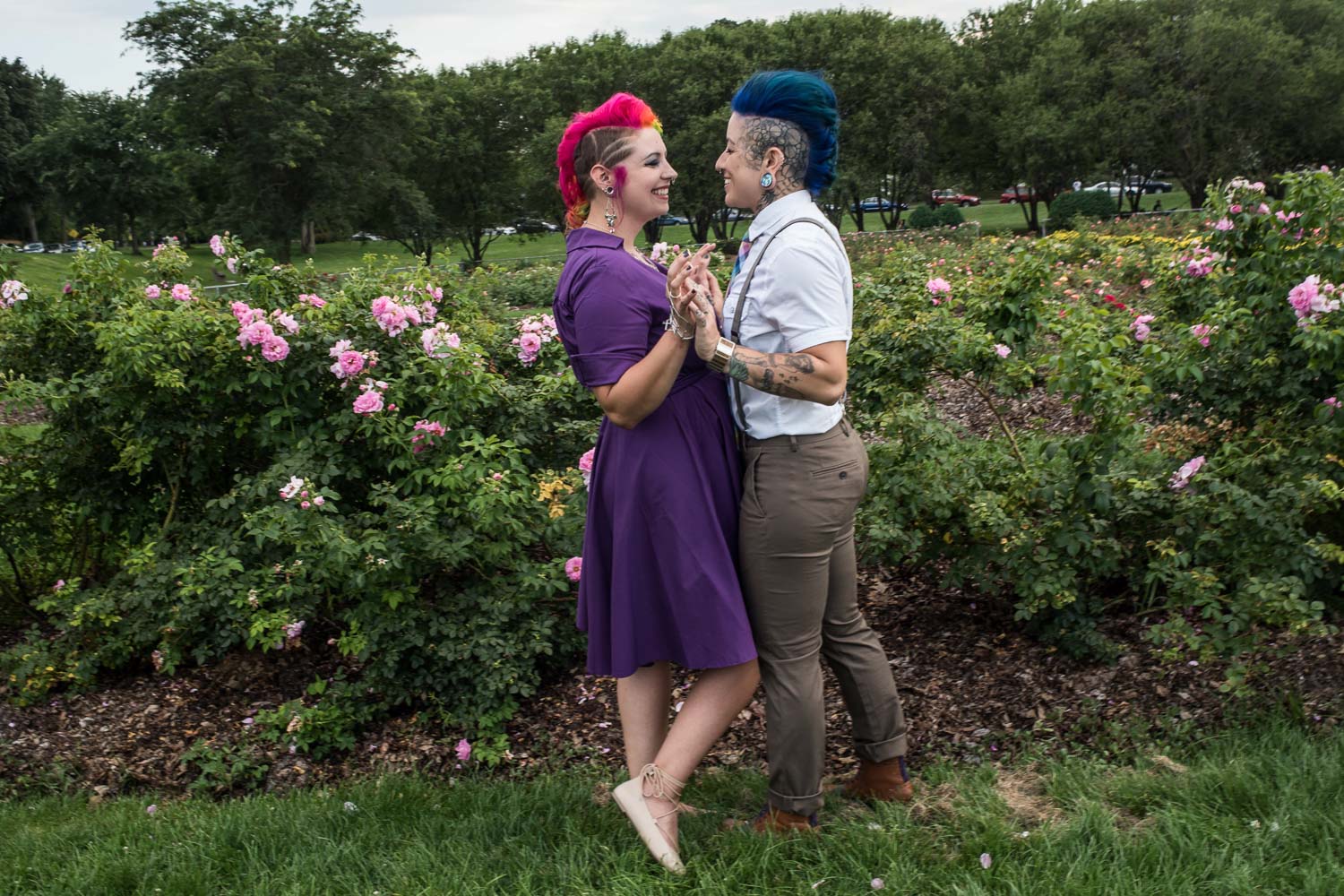woman in a purple dress with pink hair holding hands with her fiance at the rose garden in Minneapolis
