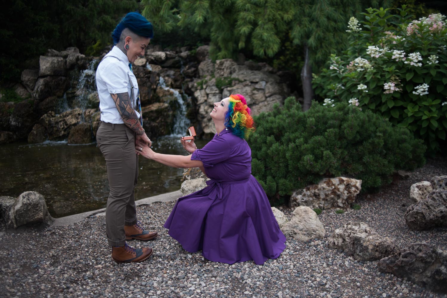 woman with rainbow colored hair kneeling to propose at the Peace garden
