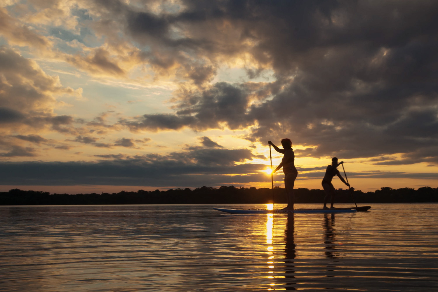 LGBTQ couple on paddleboards at sunset on Lake Harriet in Minneapolis
