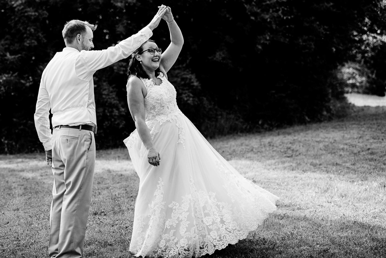 groom holding the bride's hand while she is twirling during their summer wedding at home in Minnesota
