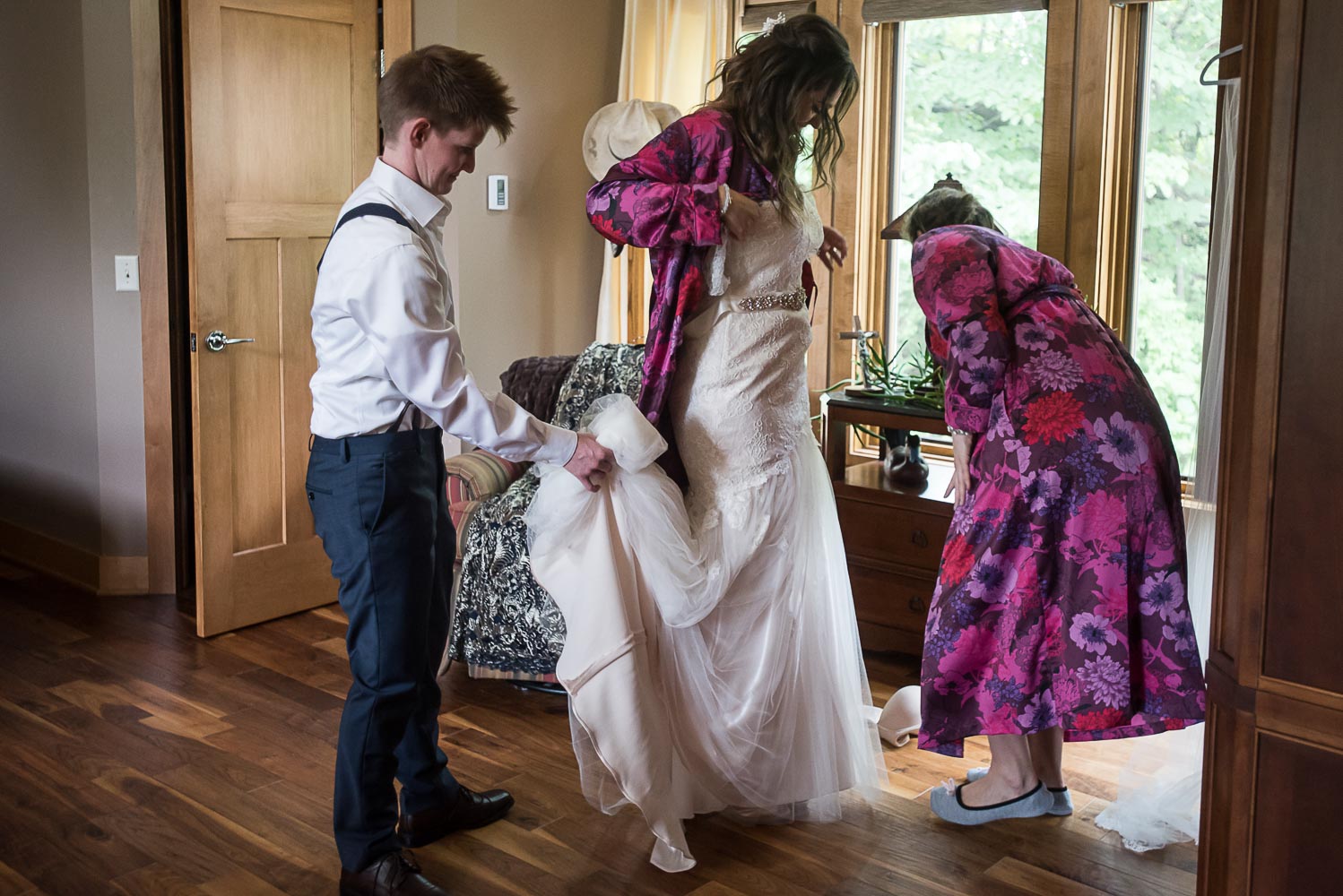 bridesmaids helping the bride put her wedding dress on