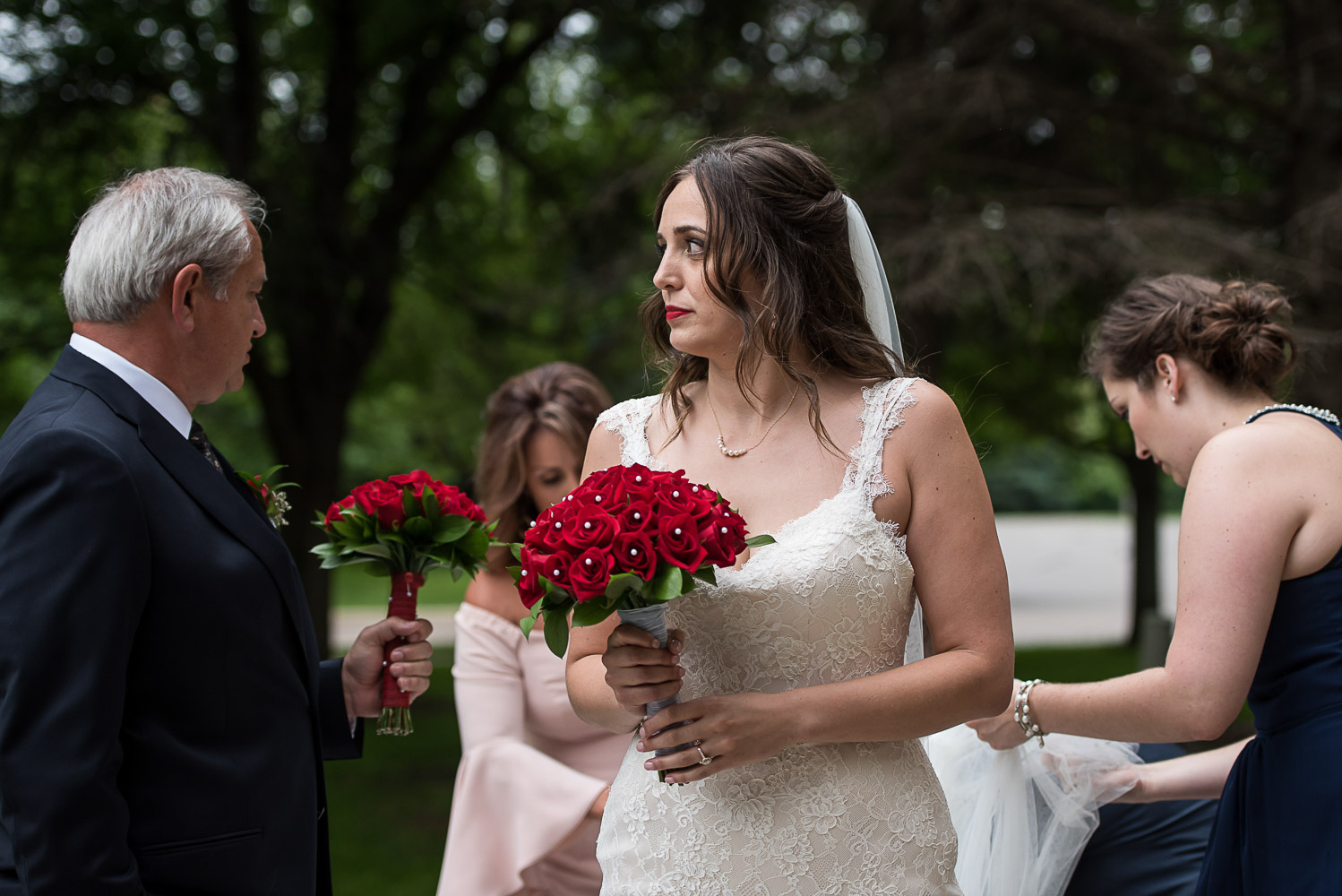 bride holding a bouquet of red roses and getting ready to walk into the wedding ceremony at St. Victoria Catholic Church