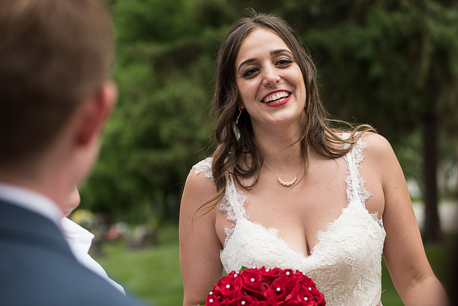 bride laughing and holding a bouquet of red roses and laughing