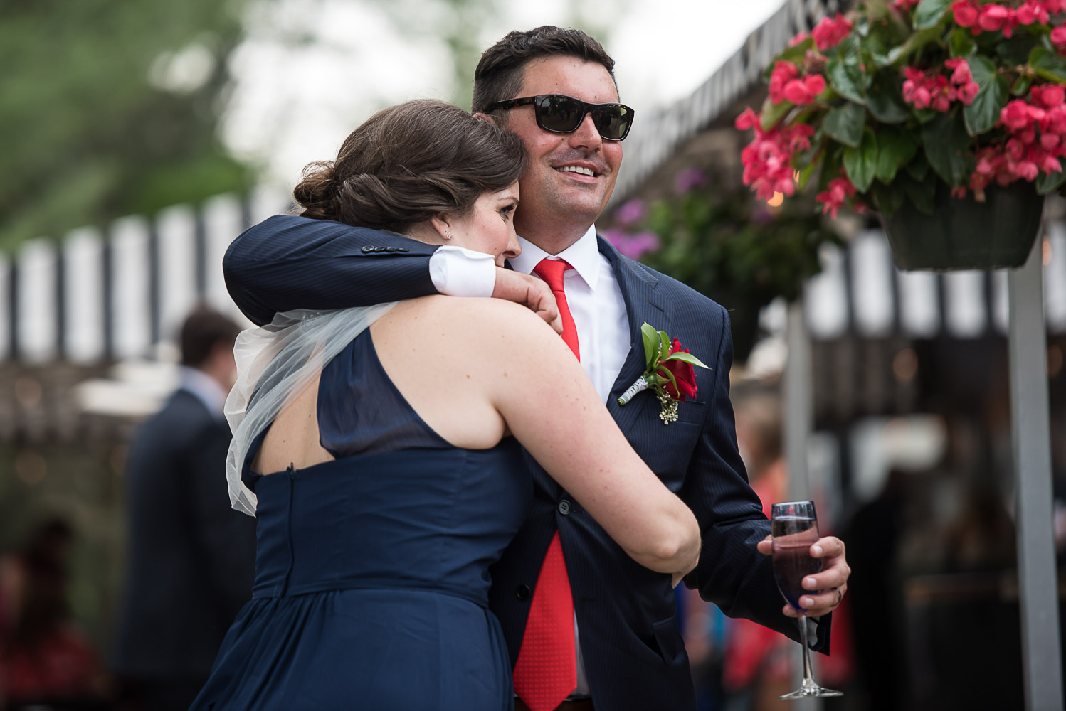 groom hugging a bridesmaid while holding a glass of wine at the Winery at Sovereign Estate