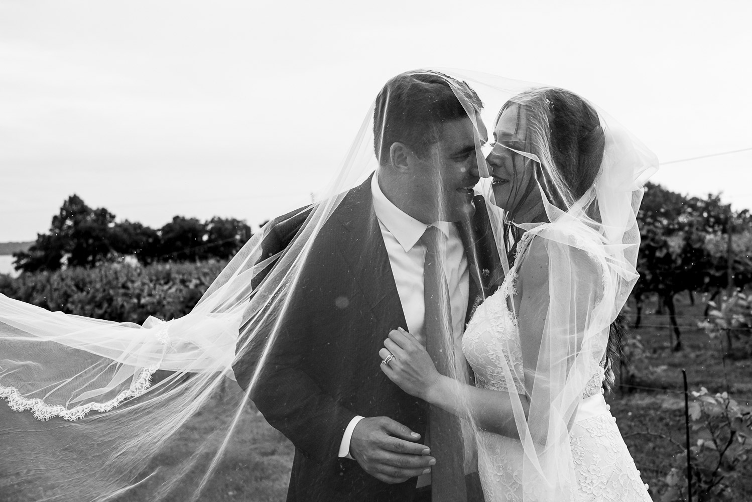 bride and groom with the veil over their faces laughing and drinking wine at the Winery at Sovereign Estate