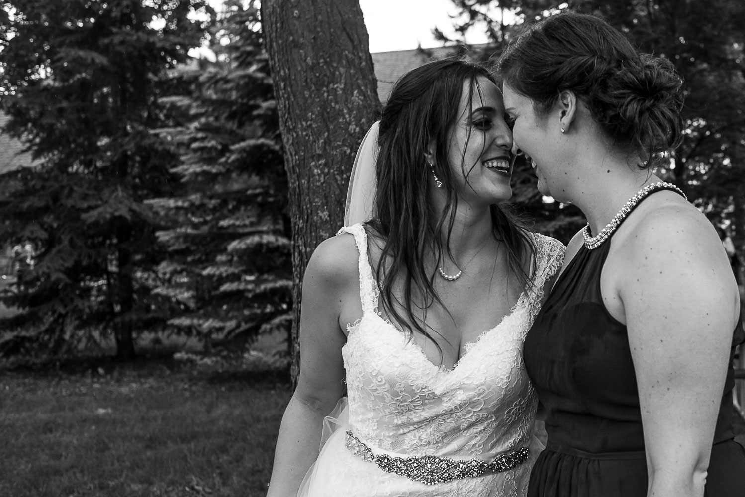 bride and bridesmaid touching foreheads and laughing in the rain at the