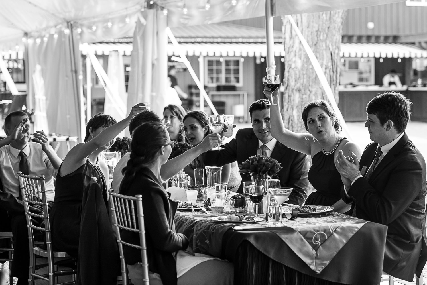 bride and groom toasting with the wedding party while they listen to speeches at the Winery at Sovereign Estate