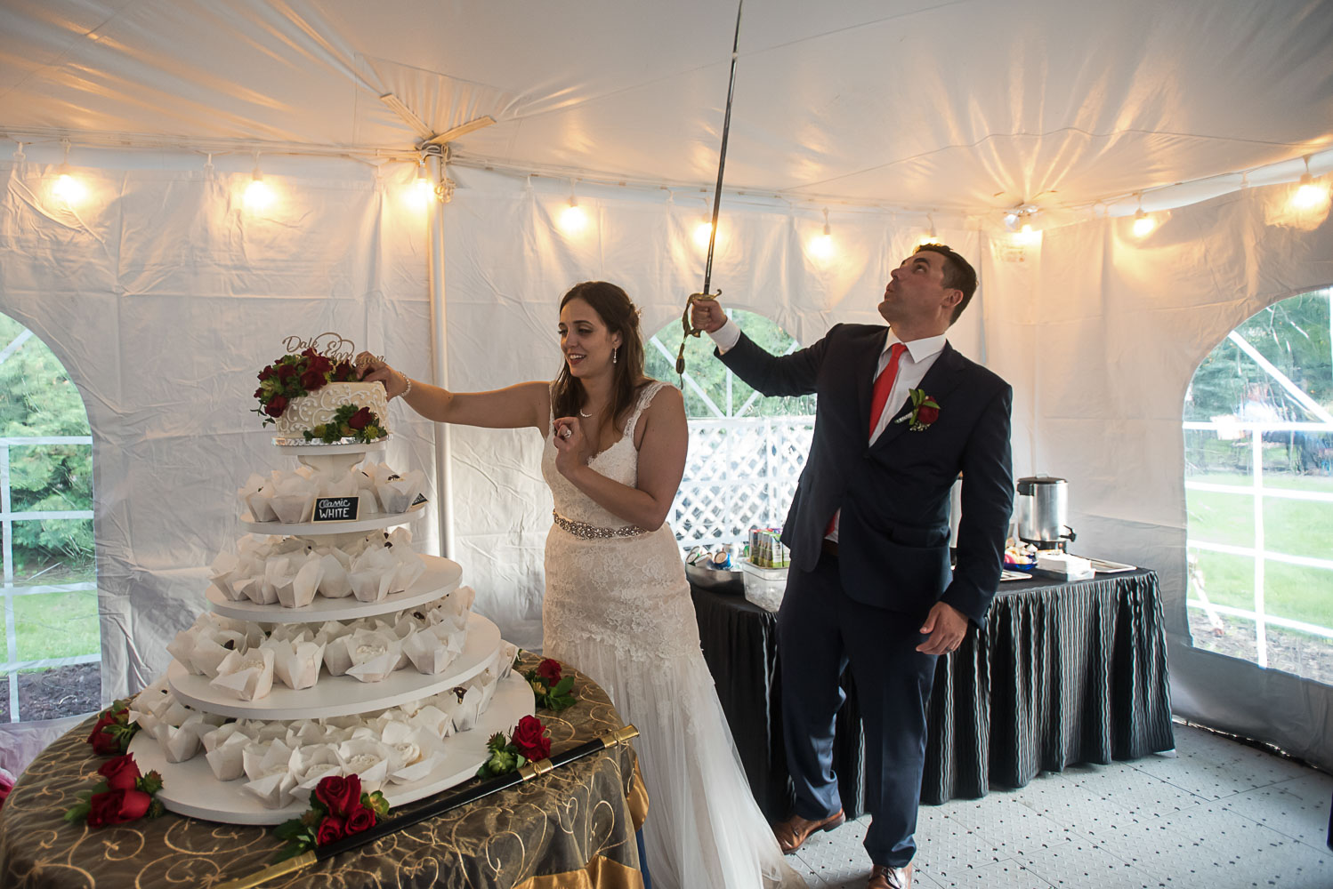 bride and groom cutting the cake with a sword at their wedding reception at bride and groom laughing while sitting at dinner at their wedding reception at the Winery at Sovereign Estate in Victoria