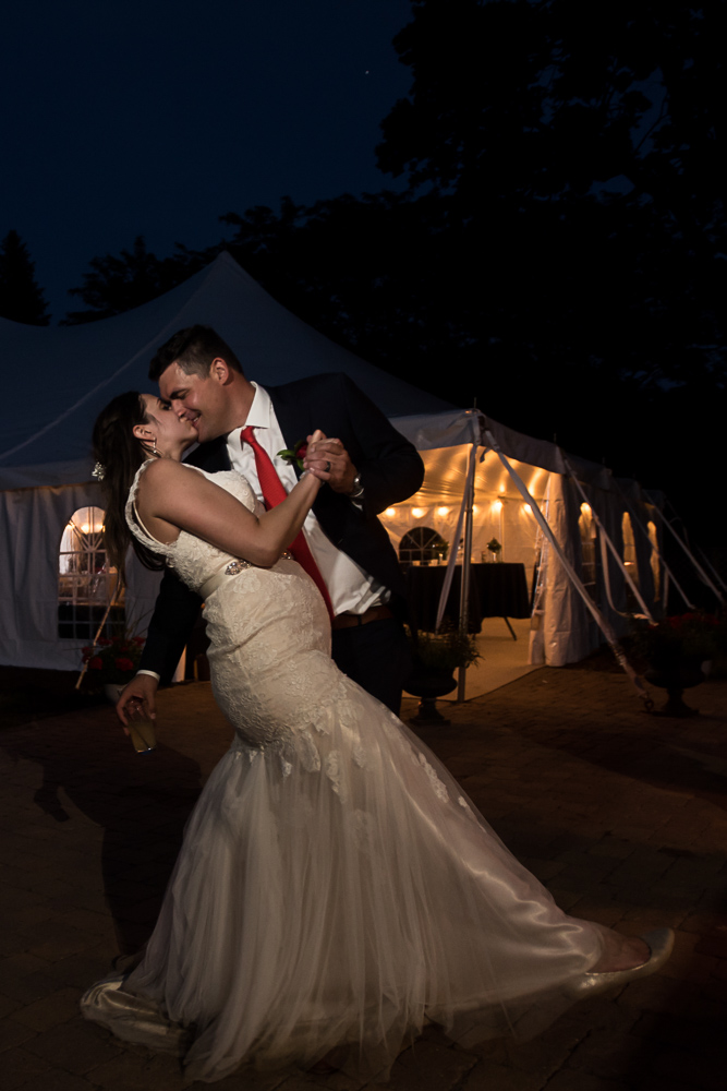 bride and groom kissing next to the wedding reception tent at Winery at Sovereign Estate in Victoria Minnesota