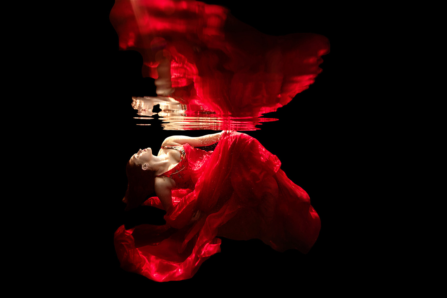underwwater fashion shoot with a woman in a red dress reflected 