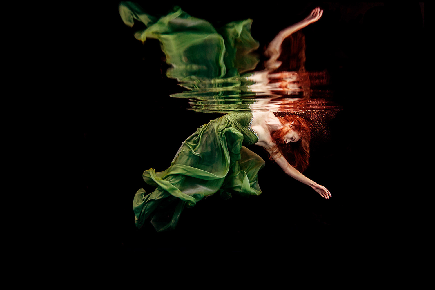 woman in a green dress with red hair underwater