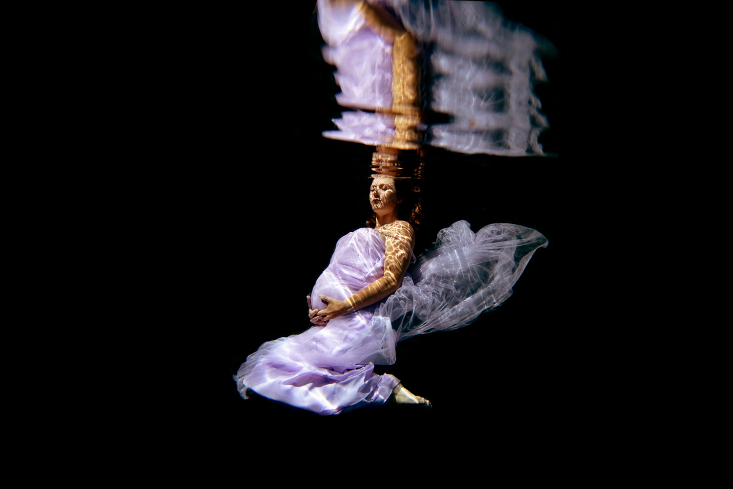 maternity session underwater wearing lavendar holding her belly