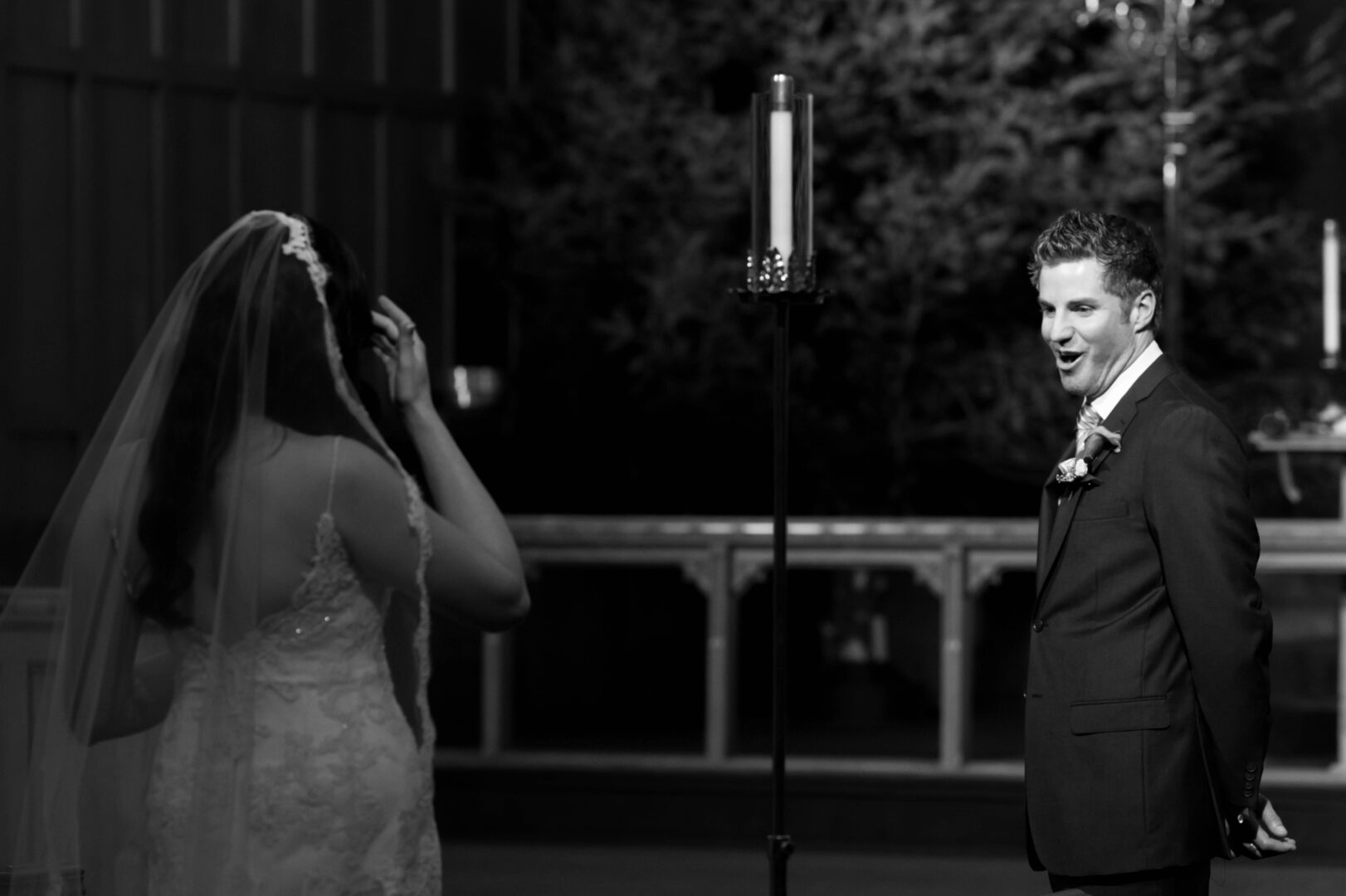 Black and white image of groom seeing bride in wedding dress for first look.