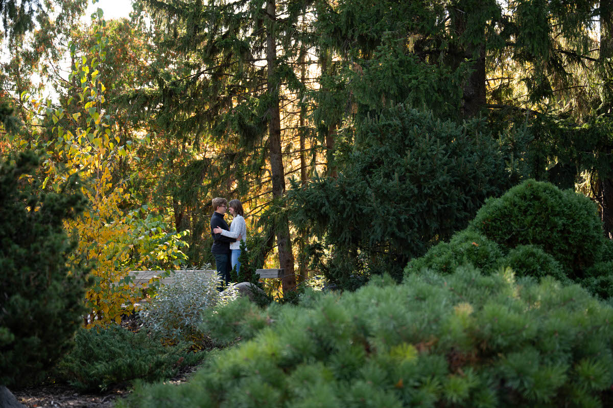 A couple smiling together while they stand in a park