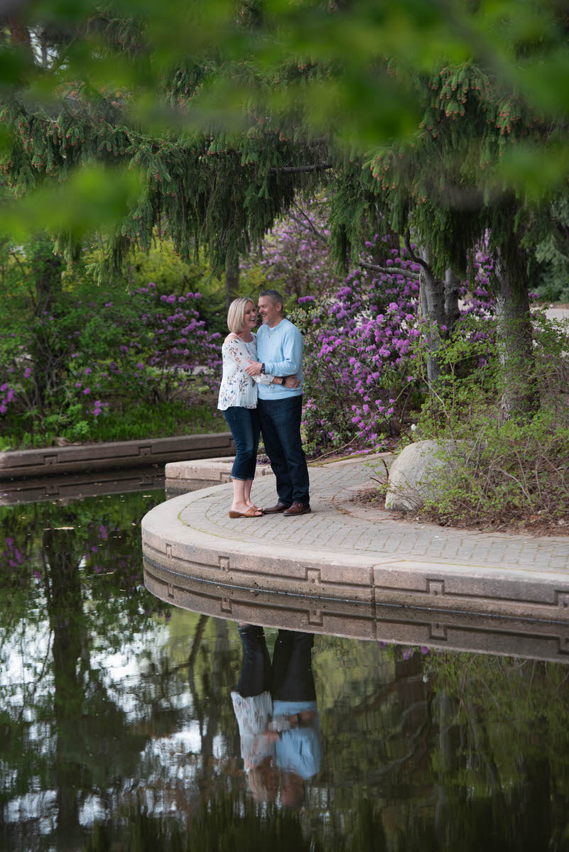 A couple laughing together while standing along the edge of a pond