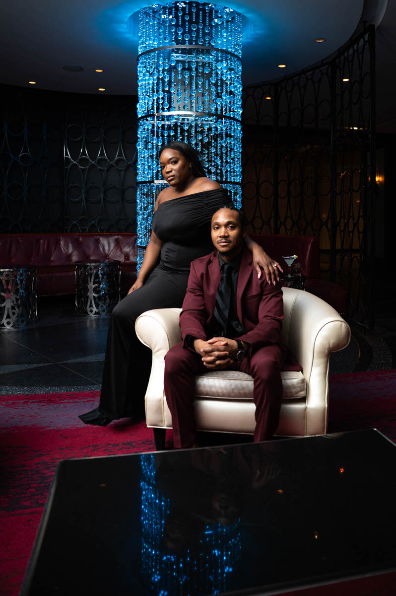 A person sitting in a chair with their partner sitting on the arm next to them