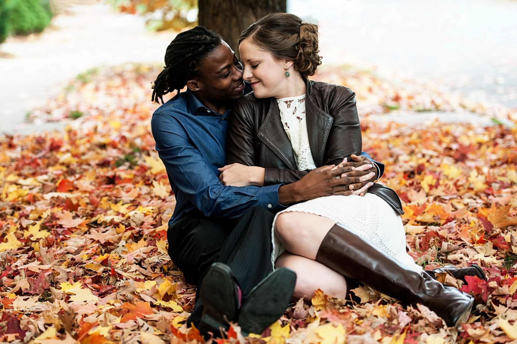a couple hugging each other underneath a tree surrounded by fall foliage on summit avenue in st paul
