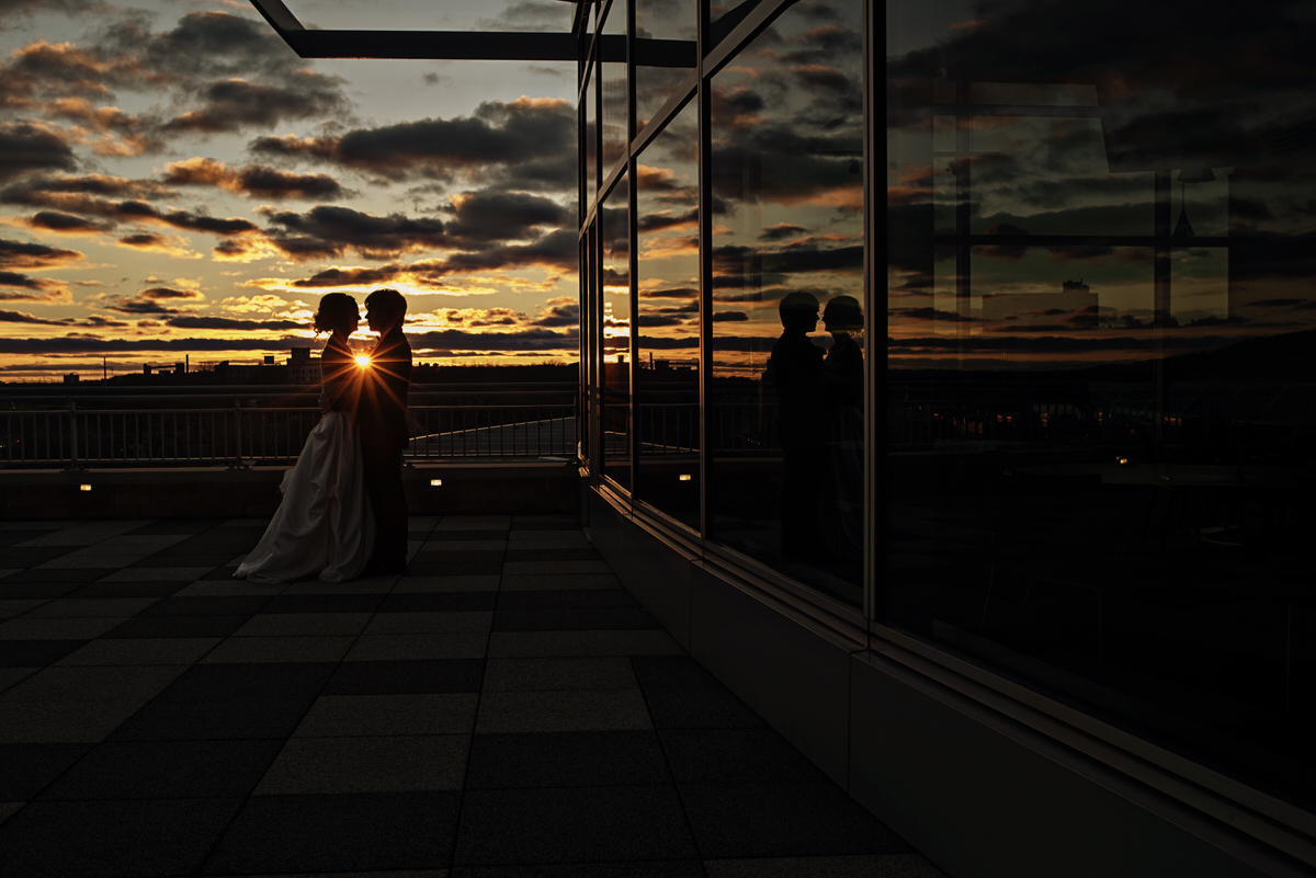a couple taking golden hour wedding portraits next to a glass building