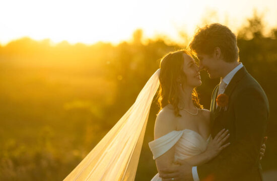 a couple taking golden hour wedding portraits in a field